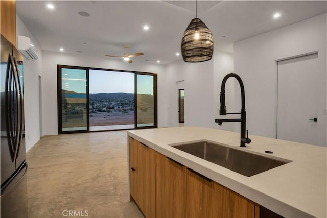 kitchen featuring black refrigerator, a wall unit AC, ceiling fan, decorative light fixtures, and sink