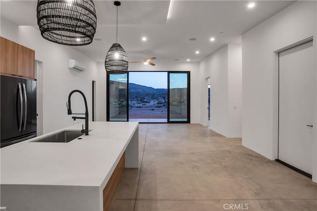 kitchen featuring hanging light fixtures, sink, black refrigerator, and a kitchen island with sink