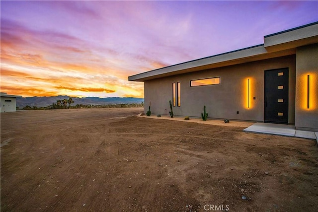 property exterior at dusk with a patio area and a mountain view