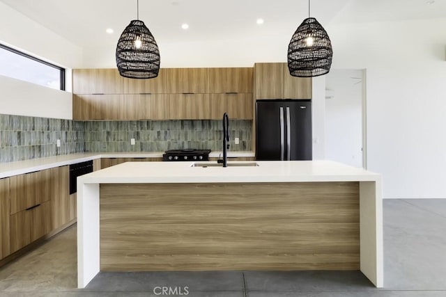 kitchen featuring black refrigerator, an inviting chandelier, and a center island with sink