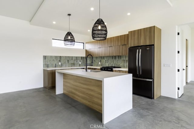 kitchen with tasteful backsplash, decorative light fixtures, a kitchen island with sink, black appliances, and sink