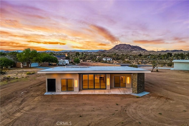 back house at dusk with a mountain view and a patio