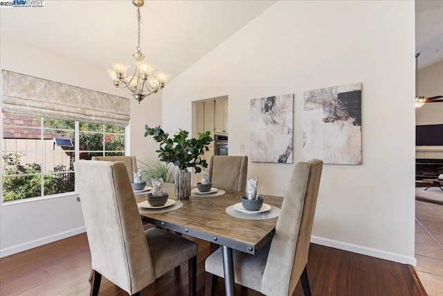 dining room featuring lofted ceiling, dark wood-type flooring, and an inviting chandelier