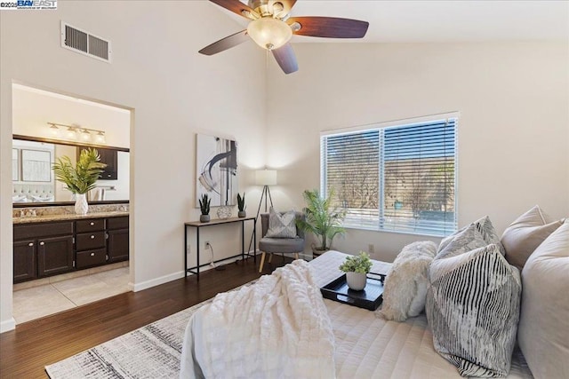 bedroom featuring wood-type flooring, ceiling fan, high vaulted ceiling, and ensuite bath