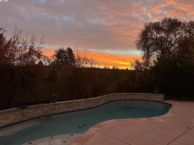 pool at dusk featuring a patio