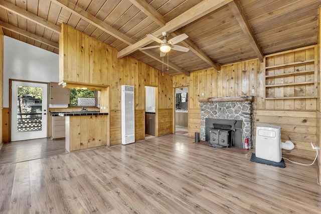 unfurnished living room with wooden ceiling, a wood stove, hardwood / wood-style floors, and beamed ceiling