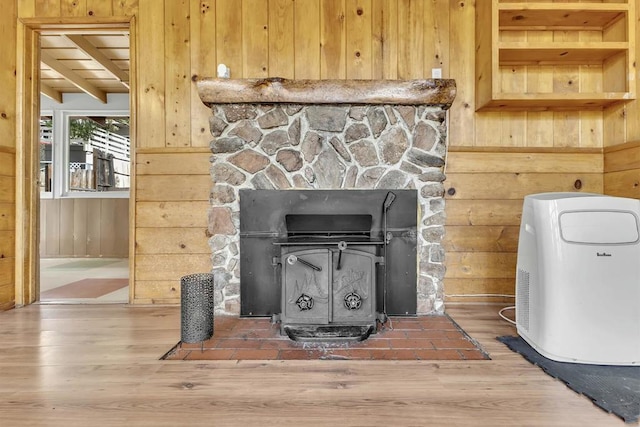 interior details with a wood stove, hardwood / wood-style floors, and wooden walls