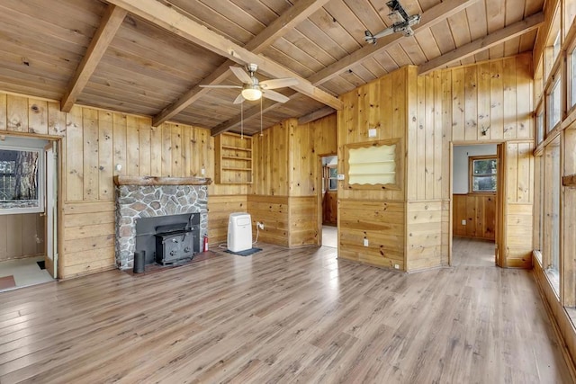 unfurnished living room with ceiling fan, hardwood / wood-style floors, wooden walls, a wood stove, and wooden ceiling