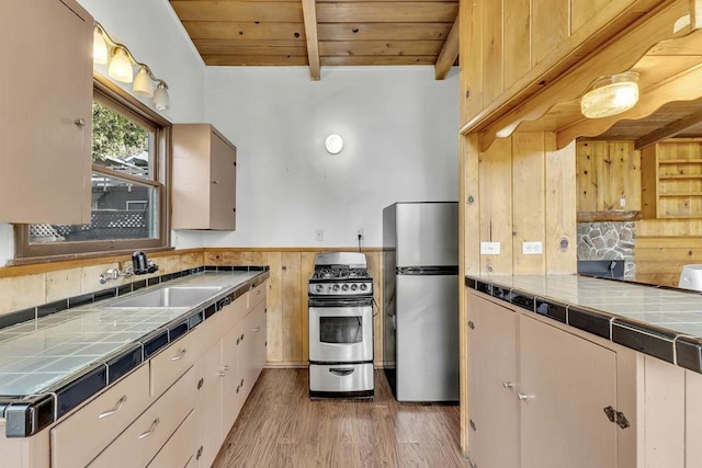 kitchen featuring tile countertops, sink, light hardwood / wood-style flooring, wood ceiling, and stainless steel appliances