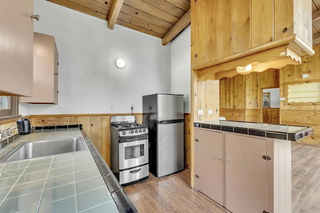 kitchen featuring appliances with stainless steel finishes, wood ceiling, sink, wood walls, and tile countertops