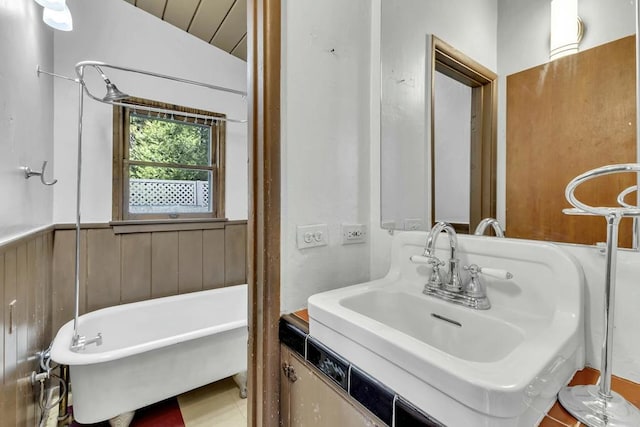 bathroom featuring a bathtub, wood walls, and sink