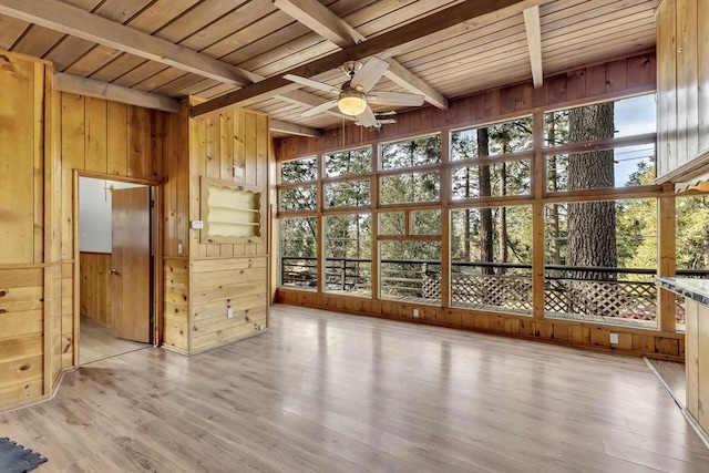 unfurnished sunroom featuring ceiling fan, wooden ceiling, and beamed ceiling