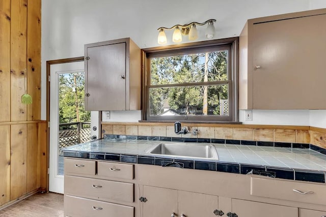 kitchen featuring tile counters, light wood-type flooring, and sink