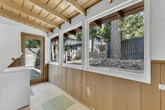 unfurnished sunroom with washer / clothes dryer, lofted ceiling with beams, wood ceiling, and a wealth of natural light