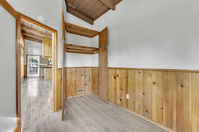 interior space with light wood-type flooring, wood walls, wood ceiling, and vaulted ceiling with beams