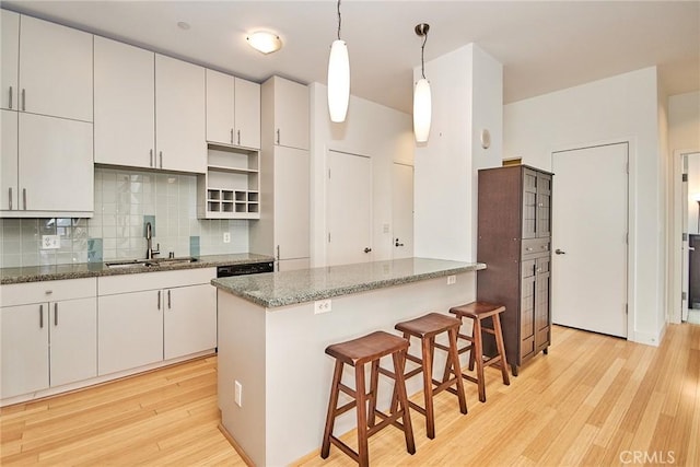 kitchen with white cabinetry, sink, tasteful backsplash, pendant lighting, and a kitchen island