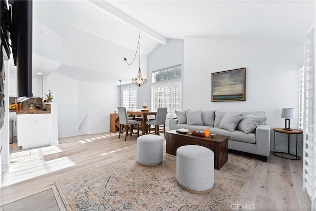 living room featuring beam ceiling, light wood-type flooring, a chandelier, and high vaulted ceiling