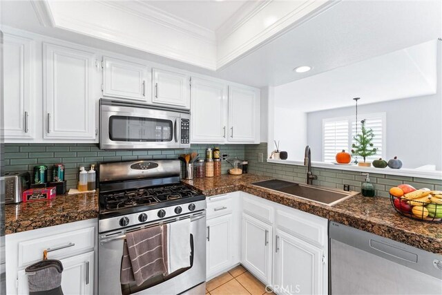 kitchen featuring pendant lighting, light tile patterned flooring, sink, white cabinetry, and stainless steel appliances