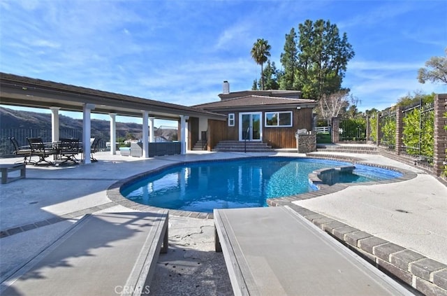 view of pool with entry steps, a pool with connected hot tub, fence, and a patio