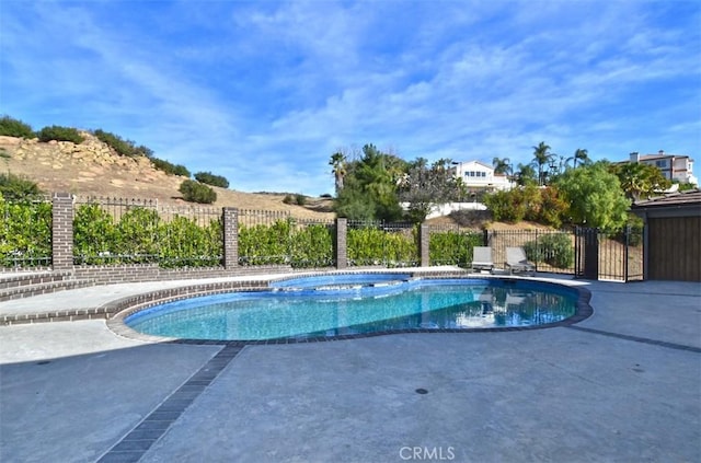 view of pool featuring a patio area, fence, a fenced in pool, and an in ground hot tub