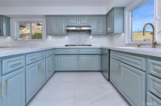 kitchen with marble finish floor, light countertops, gray cabinetry, under cabinet range hood, and a sink