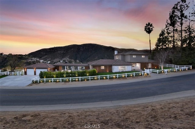 view of front of home with a fenced front yard, a mountain view, driveway, and an attached garage