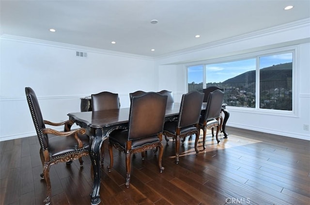 dining space featuring a mountain view, dark wood-type flooring, and crown molding