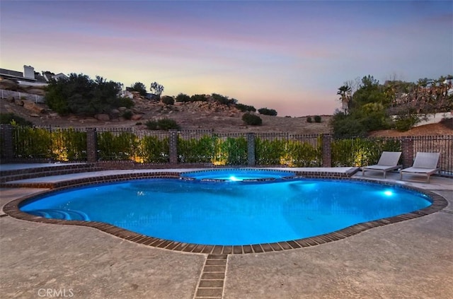 pool at dusk featuring a patio area