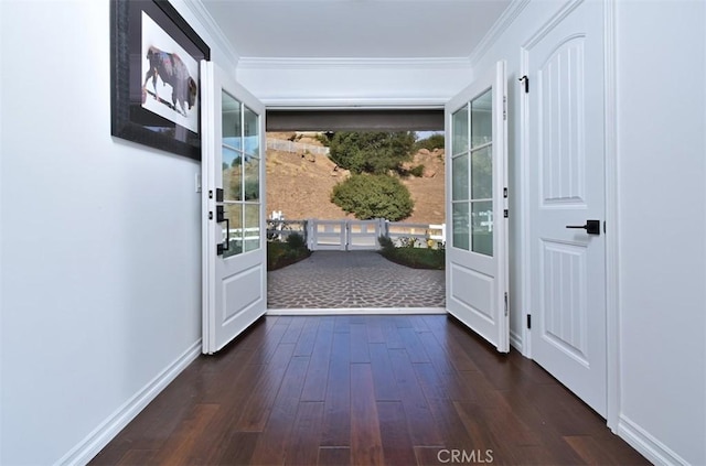 doorway featuring crown molding, baseboards, and dark wood-type flooring