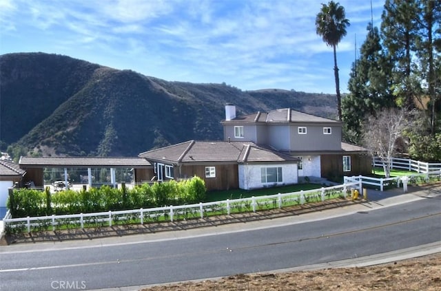 view of front facade featuring a fenced front yard, a chimney, and a mountain view