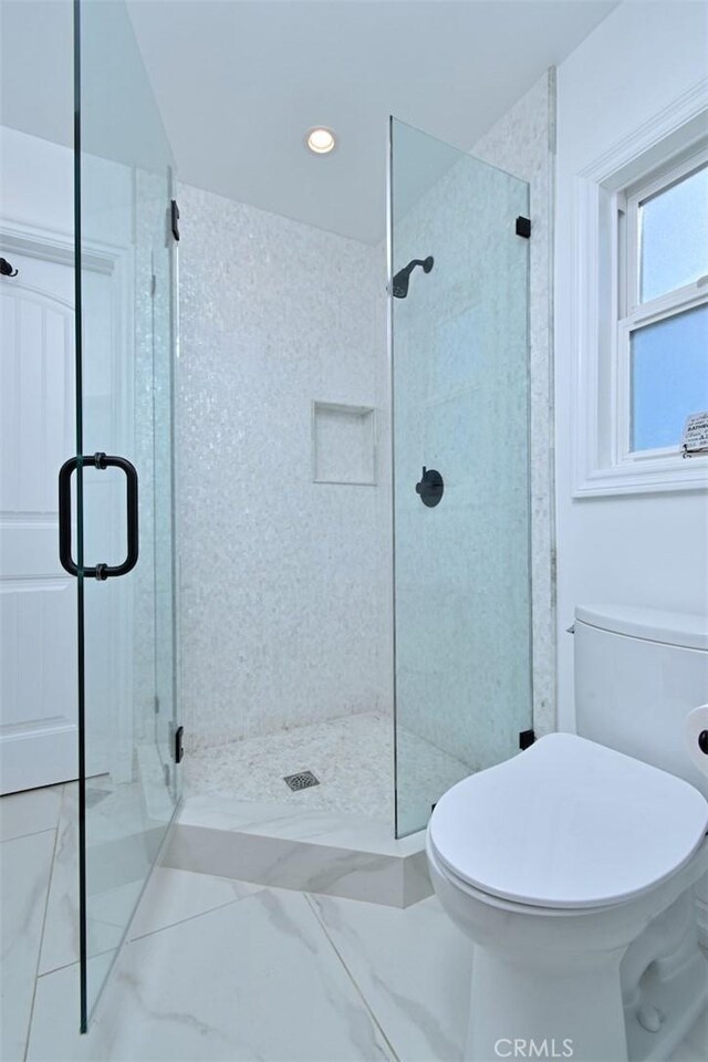 bathroom with toilet, a stall shower, and marble finish floor