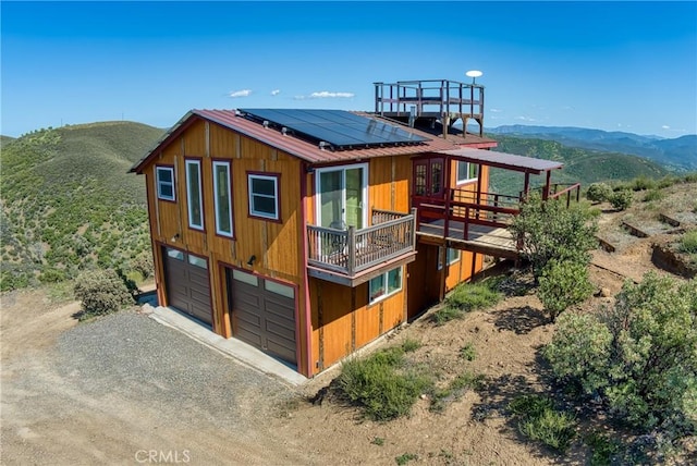 exterior space featuring a mountain view, solar panels, and a garage