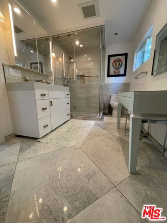 bathroom featuring toilet, walk in shower, and vanity