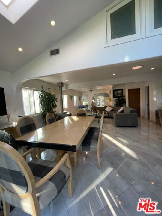 dining area with a skylight and high vaulted ceiling