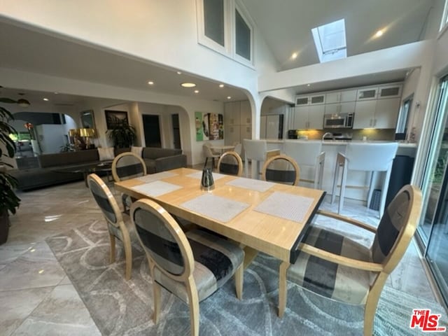 dining space with high vaulted ceiling and a skylight