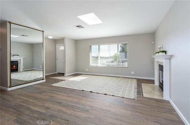 unfurnished living room with dark wood-type flooring and a skylight