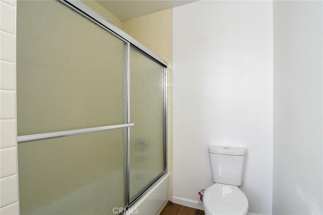 bathroom featuring enclosed tub / shower combo and toilet