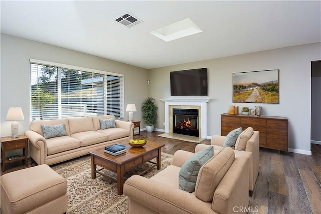 living room with a skylight and dark wood-type flooring