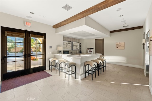 kitchen featuring french doors, kitchen peninsula, a breakfast bar area, and light tile patterned floors