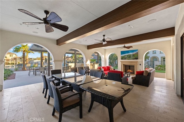 dining room featuring ceiling fan, exterior fireplace, and beam ceiling