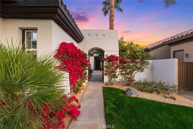 view of exterior entry featuring a gate, fence, and stucco siding