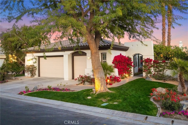 mediterranean / spanish-style house featuring a yard and a garage