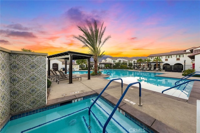 pool at dusk with a pergola and a patio area