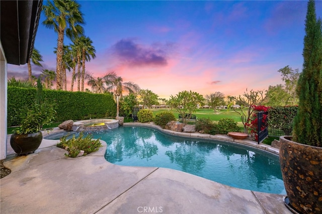 pool at dusk featuring an in ground hot tub and a patio