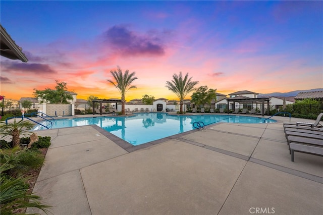 pool at dusk featuring a gazebo and a patio area