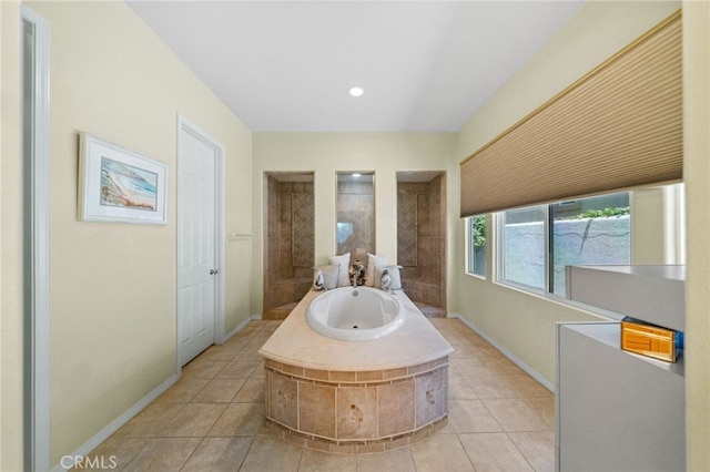 bathroom featuring tiled bath, tile patterned flooring, and sink