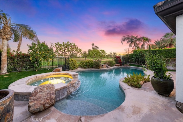 pool at dusk with an in ground hot tub