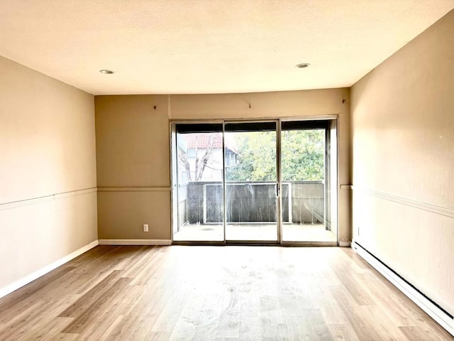 empty room featuring a baseboard radiator and light hardwood / wood-style flooring