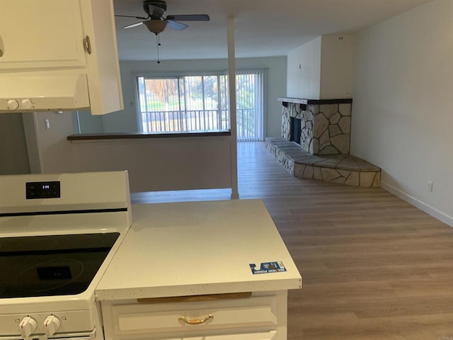 kitchen featuring white cabinets, white electric range oven, wood-type flooring, a fireplace, and ceiling fan