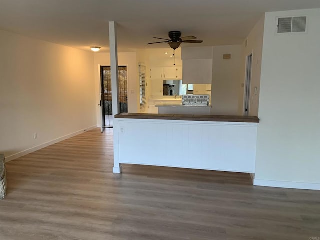 kitchen featuring ceiling fan, kitchen peninsula, white cabinetry, and hardwood / wood-style floors